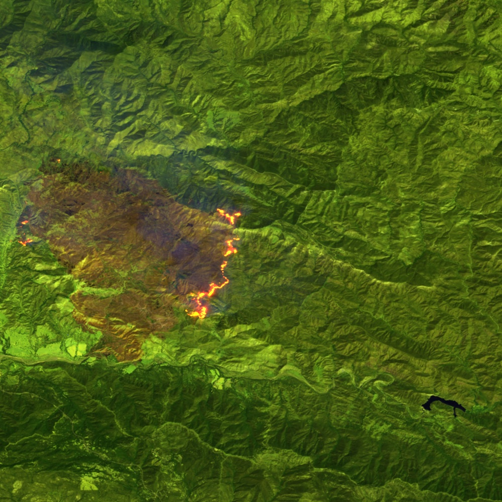 Infrared satellite scene of a wildfire, with active fronts visible as bright lines against burned ground.